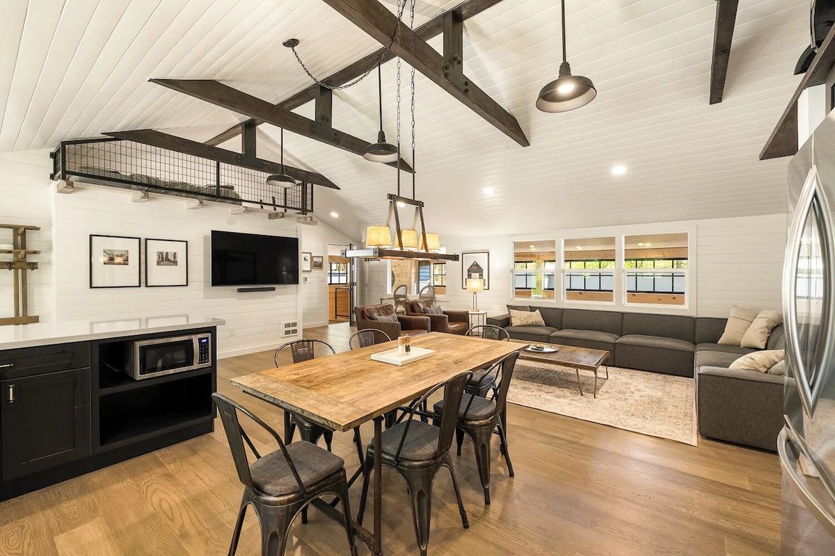 Vaulted great room with shiplap ceiling, dark beams and steel loft railing